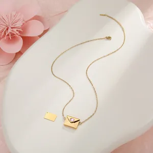 Detalle de collar con colgante de sobre dorado y piedra de corazón rosa en bandeja