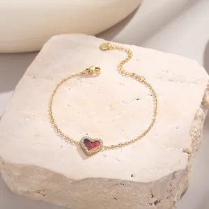 Bracelet doré élégant avec pendentif cœur rouge serti de cristaux sur fond pierre