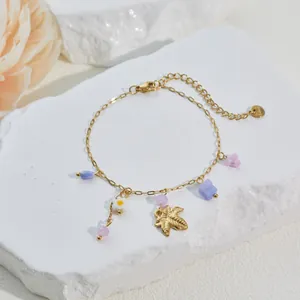 Makro-Detail von 18k vergoldetem Armband mit Blumenanhängern und Blattanhänger