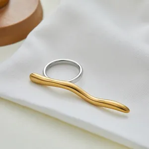 Detail van de tweekleurige zilveren ring met gouden golvende balk op witte stof