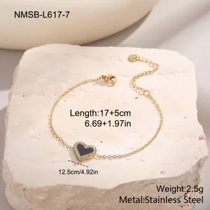 Gros plan sur un bracelet en acier doré avec pendentif cœur noir et cristaux brillants