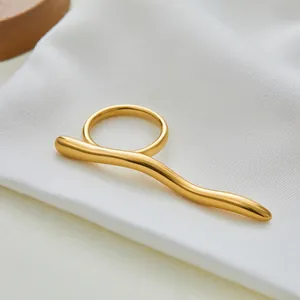 Macro-opname van een gepolijste gouden geometrische golfring op een witte stoffen achtergrond