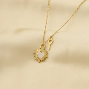 Collar dorado con colgante de candado de corazón y llave sobre fondo de seda champán