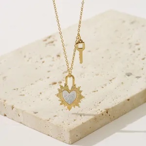 Collar dorado con colgante de corazón solar y piedra blanca sobre soporte de piedra