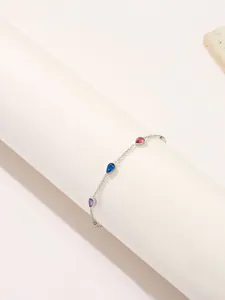Detail van 18K goud titaniumstalen armband met kleurrijke peervormige zirkonia's