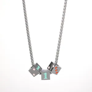 Macro view of dice cube pendants on wheat chain with number one and colorful dots
