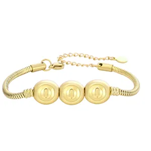 Détail d'un bracelet serpent doré orné de trois perles polies avec le chiffre porte-bonheur 0