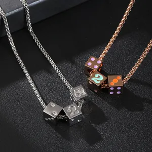 Detail of silver and rose gold dice pendants on wheat chains with enamel accents