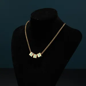 Macro detail of gold dice pendants with blue number one on a woven chain necklace