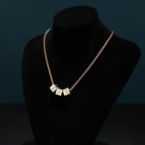 Close-up of rose gold dice cube pendants with number one detail on black bust stand