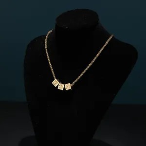Close-up of golden number 2 dice cube pendants on a stylish twist chain necklace