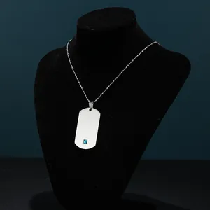 Detalle del collar con colgante rectangular plateado y gema azul en busto negro