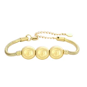 Détail du bracelet à boules dorées montrant le chiffre 3 gravé sur les perles