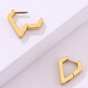 Vista macro detallada de pendientes de aro geométricos de acero inoxidable bañados en oro