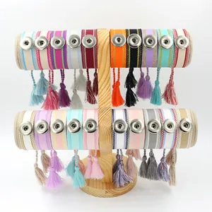 Detail view of woven DIY button bracelets with tassels displayed on a wooden stand
