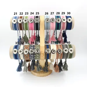 Pulseras étnicas bohemias tejidas con botones a presión y borlas en un soporte de madera