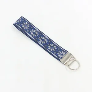 Close-up of geometric jacquard woven keychain with snowflake pattern and silver metal clasp