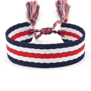 Detail of woven fabric bracelet with navy, red, and white stripes and fringed tassels