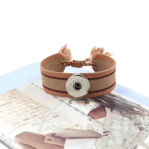 Detalle de pulsera boho tejida con botón a presión plateado y flecos de borlas largos
