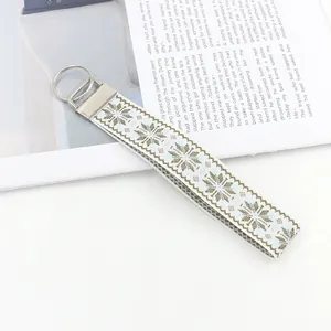 Ethnic style woven snowflake jacquard webbing keychain with silver ring and book background
