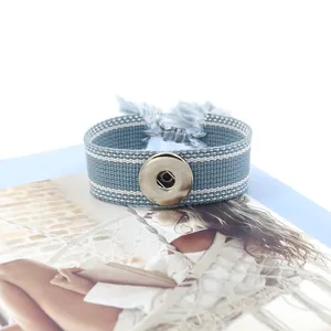 Détail du bracelet tressé bleu DIY à bouton-pression avec rayures blanches et pompon