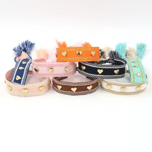 Handwoven friendship bracelets with golden heart studs and colorful tassels in various shades