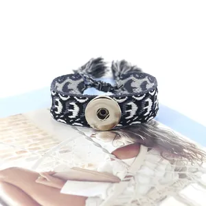 Detalle macro de una pulsera boho tejida con botón a presión y patrones geométricos