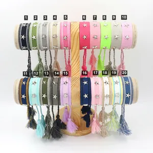 Detalle de pulseras tejidas de colores con estrellas plateadas y borlas en soporte de madera