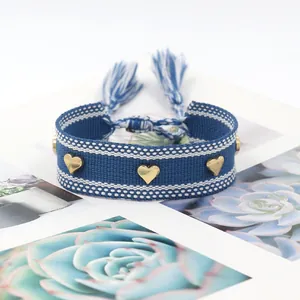Close-up of handmade woven blue and white bracelet with three golden heart-shaped studs