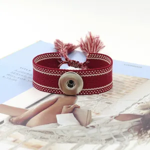 Gros plan du bracelet tissé rouge avec bouton pression argenté et détails de franges