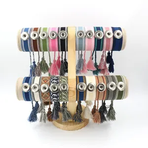 Pulseras tejidas bohemias coloridas con cierres metálicos y borlas en soporte de madera