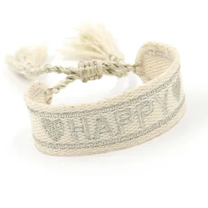 Gedetailleerde macro-opname van geweven armband met zilveren HAPPY-letters en kwastjes