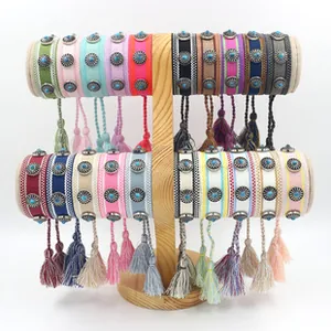 Dettaglio di bracciali boho intrecciati con borchie turchesi e lunghe nappe colorate