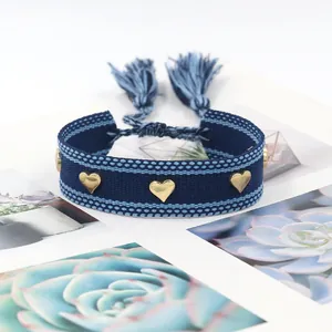 Detail of blue woven friendship bracelet with golden heart studs and tassels