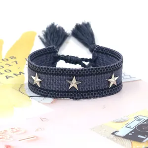 Detalle de pulsera trenzada con estrellas plateadas, borlas y nudo de cierre ajustable