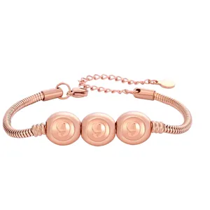 Gros plan sur un bracelet chaîne serpent en or rose avec trois billes gravées du chiffre 999
