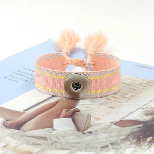 Gros plan détaillé du bracelet tissé rose et jaune avec bouton pression et glands doux