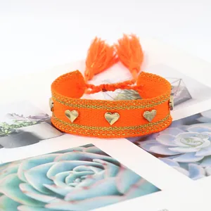 Handmade woven orange friendship bracelet with golden heart studs and tassels