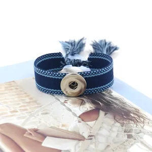 Detalle de pulsera tejida boho con botón de presión plateado y borlas azules