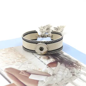 Detalle macro de la pulsera tejida bohemia con botón de presión plateado y flecos