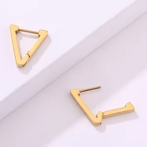 Detalle macro de pendientes de aro dorados en forma de V con acabado metálico pulido