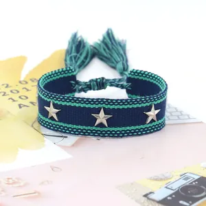 Detalle de pulsera tejida azul con tachuelas de estrellas y flecos de estilo étnico