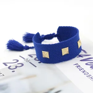 Gros plan sur le bracelet d'amitié tissé bleu avec clous dorés et détails de pompons