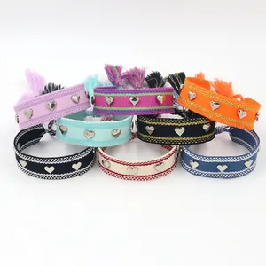 Détail de bracelets bohèmes tissés avec clous cœurs argentés et glands en diverses couleurs
