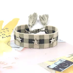 Vista detallada de la pulsera tejida a cuadros con estrellas de metal vintage y borlas