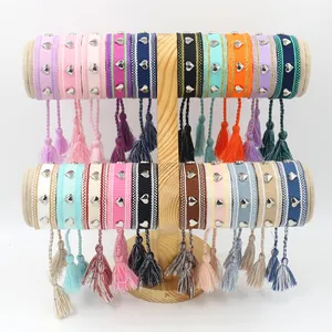 Détail de bracelets tissés bohèmes colorés avec rivets en cœur sur support bois
