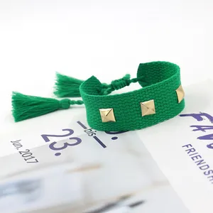 Détail du bracelet tissé vert émeraude avec clous pyramidaux dorés et pompons chic