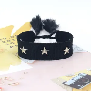 Pulsera trenzada negra con dijes de estrellas plateadas y borlas en una vista plana