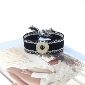 Detalle de la pulsera bohemia tejida en blanco y negro con botón de presión y borlas