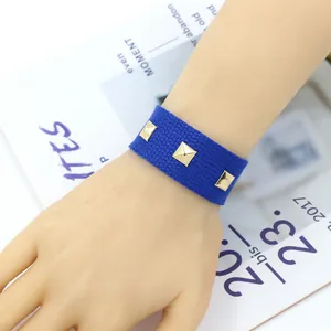 Gros plan du bracelet tissé bleu roi orné de trois clous pyramides dorés polis